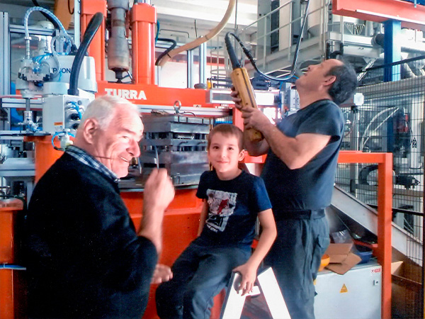 Nonno, padre e figlio della famiglia Zinesi con Macchinario Turra sullo sfondo